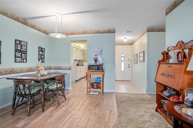 dining space with light hardwood / wood-style floors and a textured ceiling