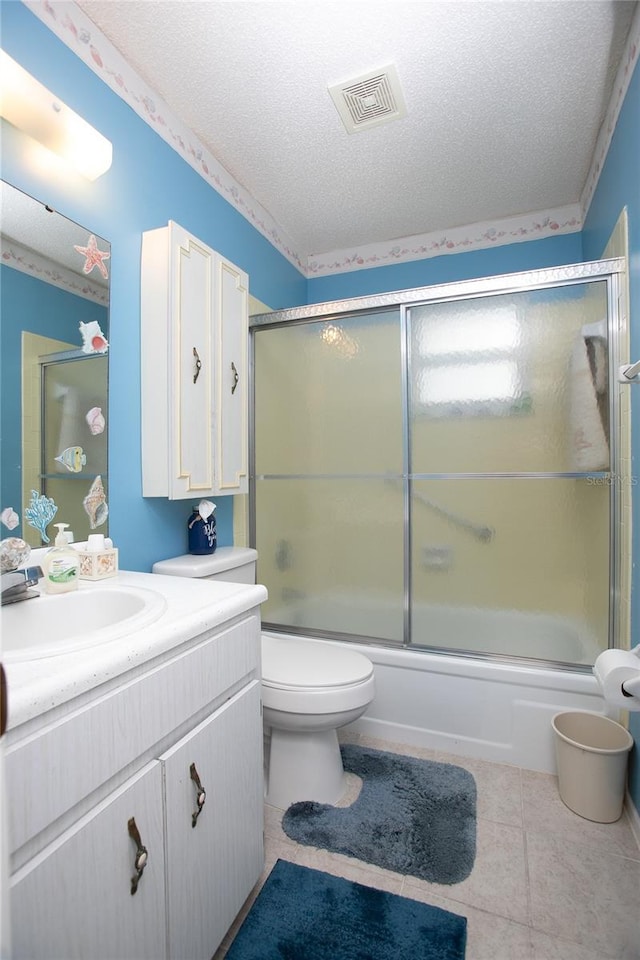 full bathroom featuring vanity, a textured ceiling, shower / bath combination with glass door, tile patterned flooring, and toilet