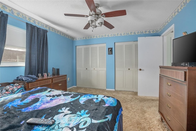 carpeted bedroom with multiple closets, ceiling fan, and a textured ceiling