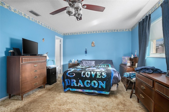 carpeted bedroom featuring ceiling fan and a textured ceiling