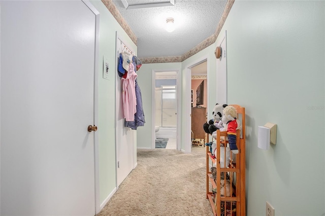 hallway with light colored carpet and a textured ceiling