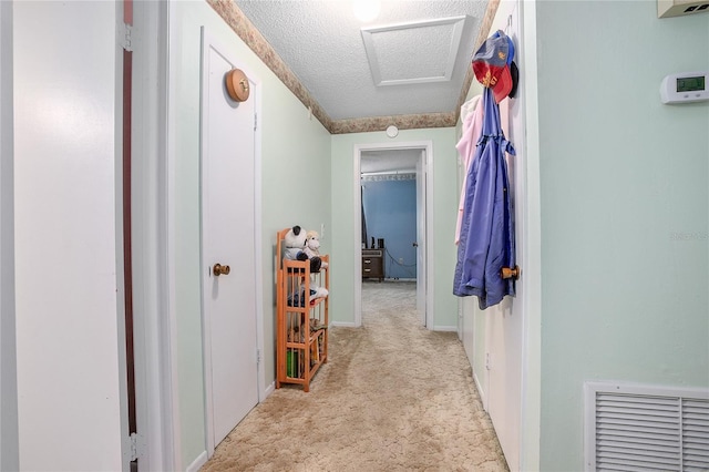 corridor with light colored carpet and a textured ceiling