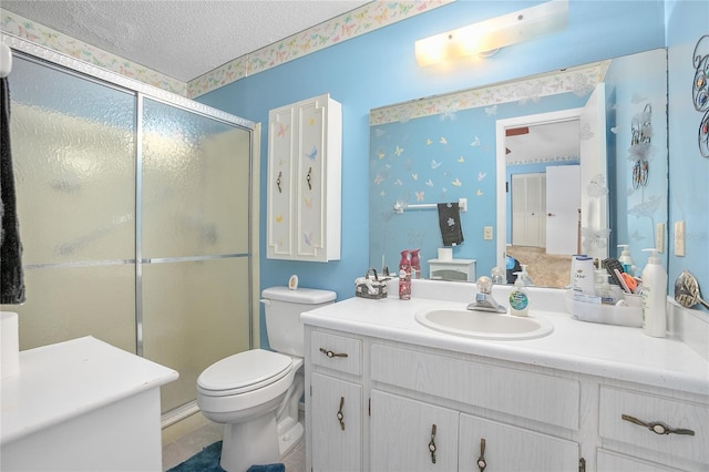 bathroom with vanity, a shower with shower door, a textured ceiling, and toilet