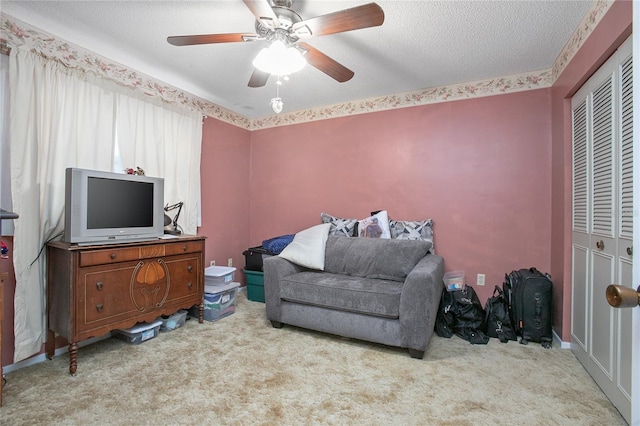 living area featuring a textured ceiling, ceiling fan, and light carpet