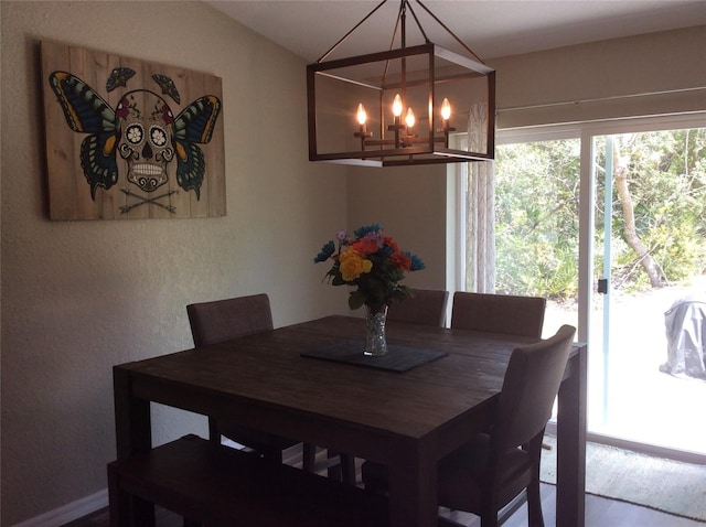 dining area with hardwood / wood-style floors, a chandelier, and lofted ceiling