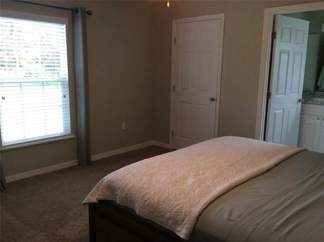 bedroom featuring dark colored carpet and connected bathroom