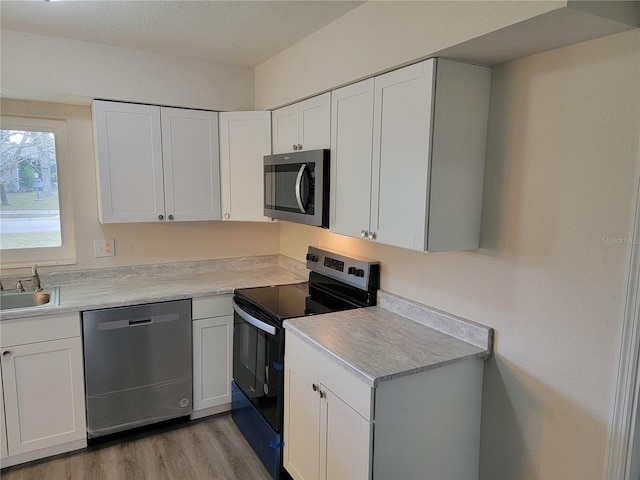 kitchen featuring white cabinets, light hardwood / wood-style floors, sink, and appliances with stainless steel finishes