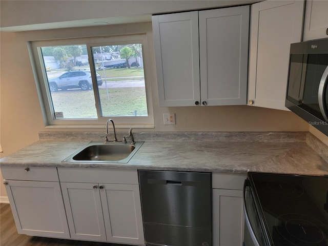 kitchen featuring black electric range, white cabinets, stainless steel dishwasher, and sink