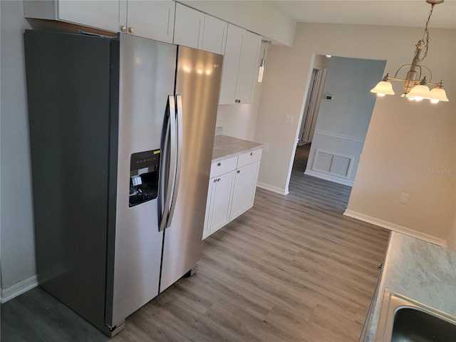 kitchen featuring light wood-type flooring, pendant lighting, white cabinets, stainless steel fridge with ice dispenser, and a chandelier