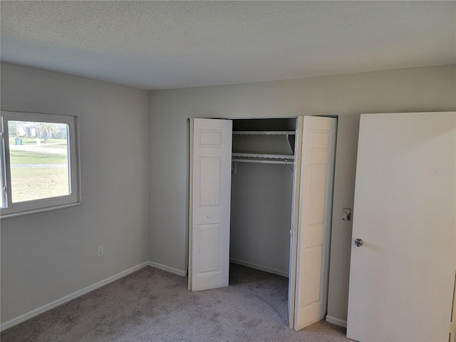 unfurnished bedroom with light carpet, a closet, and a textured ceiling