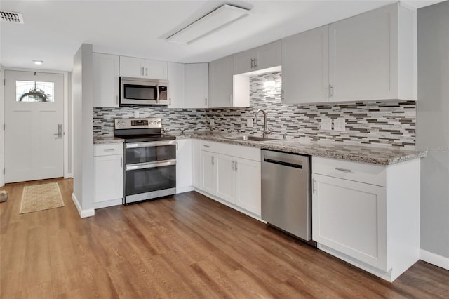 kitchen with backsplash, stainless steel appliances, white cabinetry, and sink