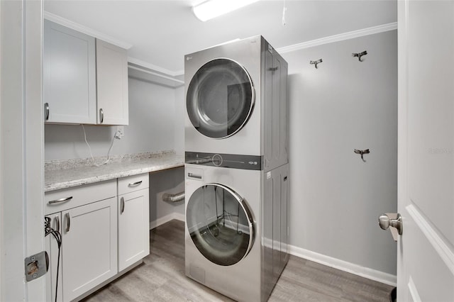 laundry room featuring light hardwood / wood-style flooring, cabinets, crown molding, and stacked washer and clothes dryer