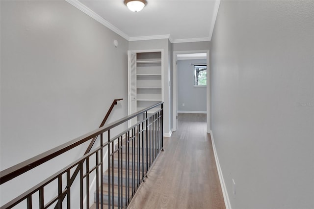 hall featuring built in shelves, hardwood / wood-style flooring, and crown molding