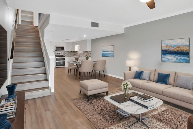 living room featuring ceiling fan, light hardwood / wood-style floors, and ornamental molding