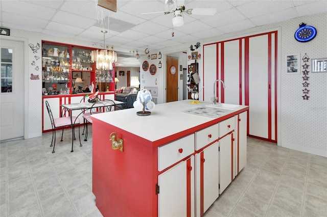 kitchen with a paneled ceiling, pendant lighting, a center island, and white cabinetry