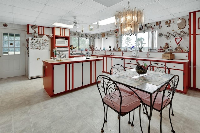 kitchen with a kitchen island, white appliances, a drop ceiling, and pendant lighting