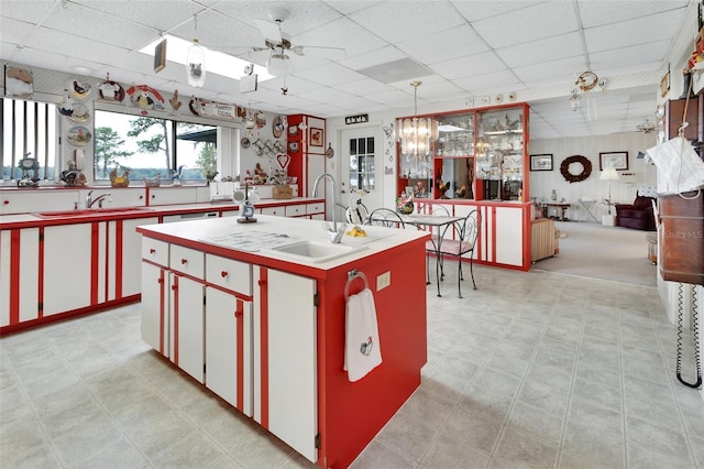 kitchen with sink, ceiling fan, hanging light fixtures, and a kitchen island with sink