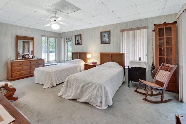 bedroom featuring light carpet, a drop ceiling, and ceiling fan