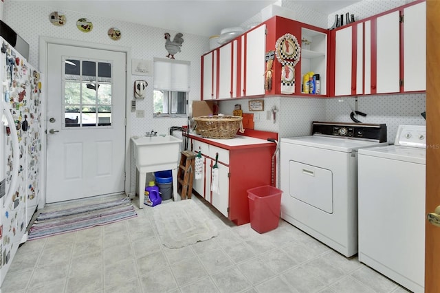 clothes washing area with cabinets and washer and dryer