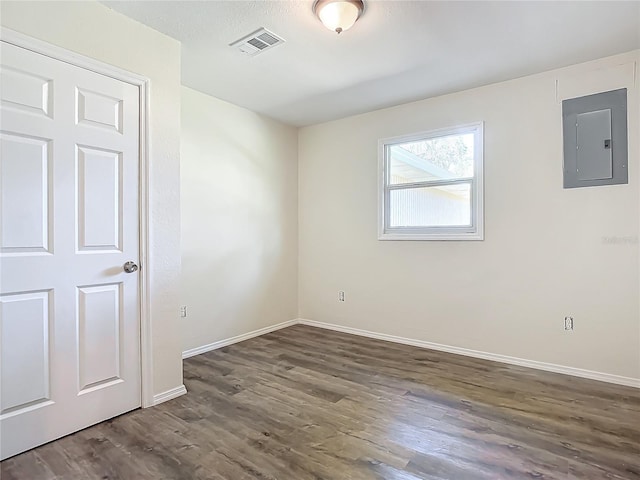 unfurnished room featuring electric panel and dark hardwood / wood-style floors