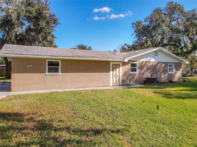 back of property with a lawn and central AC