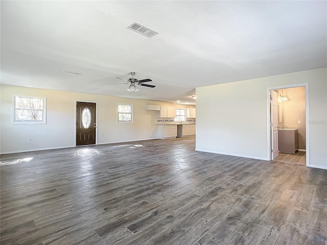 unfurnished living room with ceiling fan, a healthy amount of sunlight, and dark hardwood / wood-style flooring