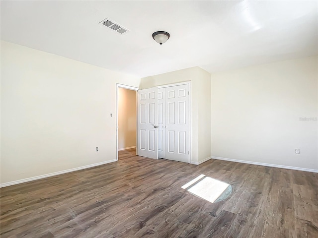 unfurnished bedroom featuring dark hardwood / wood-style floors and a closet