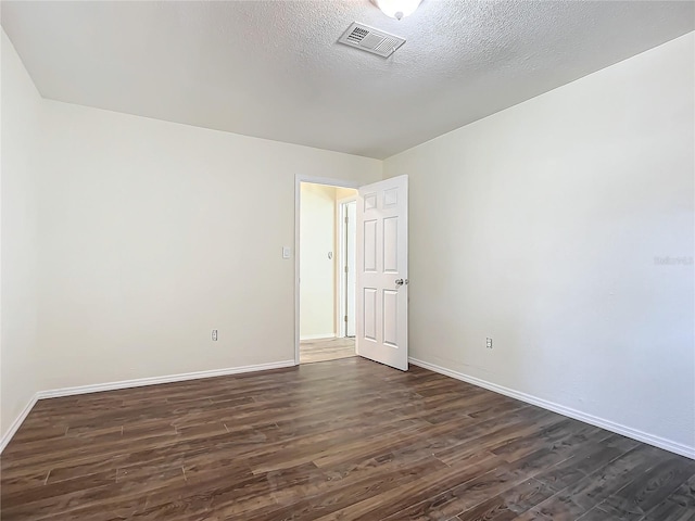 spare room featuring dark hardwood / wood-style floors and a textured ceiling