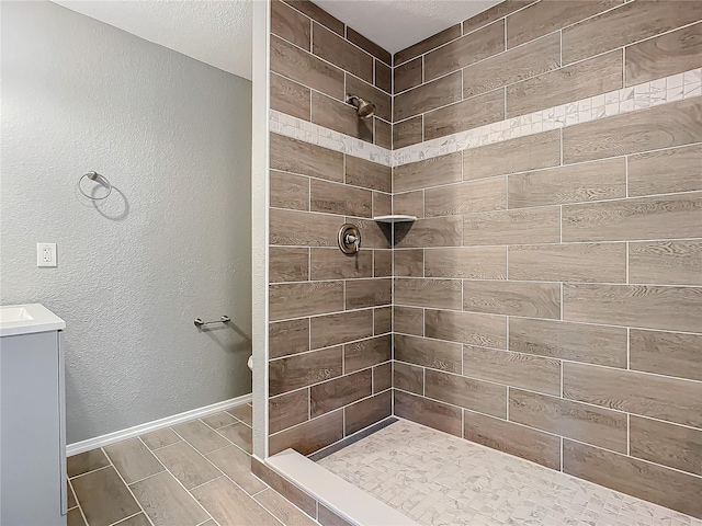 bathroom with a tile shower and vanity