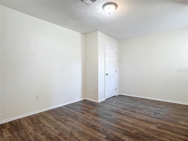 spare room featuring a textured ceiling and dark hardwood / wood-style floors