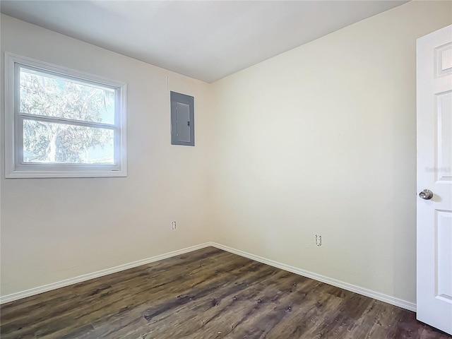 empty room with dark hardwood / wood-style flooring and electric panel