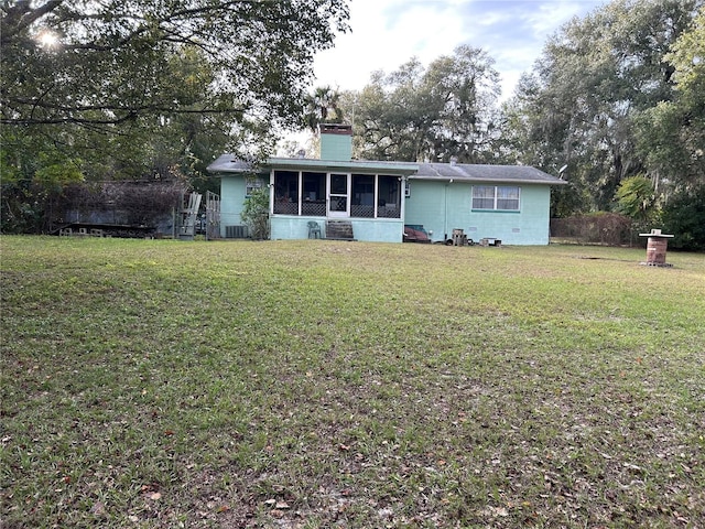 view of front of home with cooling unit, a sunroom, and a front lawn