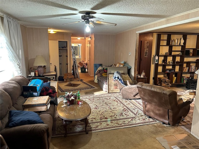 living room with wooden walls, ceiling fan, and a textured ceiling