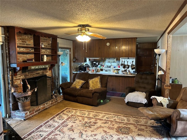 carpeted living room featuring ceiling fan, wood walls, a textured ceiling, and a brick fireplace