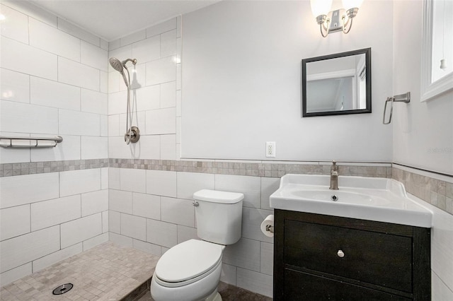 bathroom featuring a tile shower, vanity, tile walls, and toilet