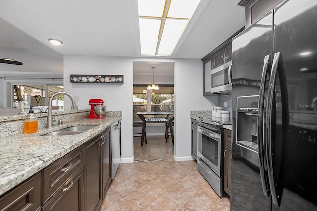 kitchen with plenty of natural light, sink, stainless steel appliances, and decorative light fixtures