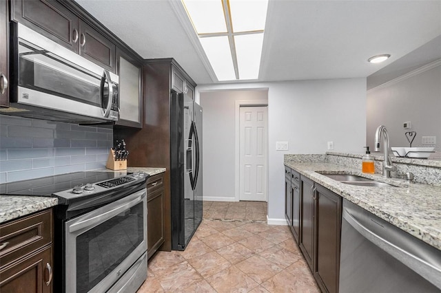 kitchen featuring dark brown cabinetry, light stone counters, sink, and appliances with stainless steel finishes