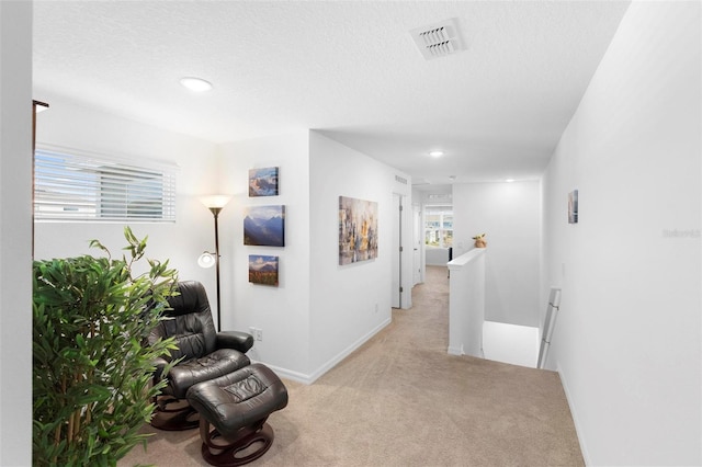 corridor featuring a textured ceiling and light colored carpet