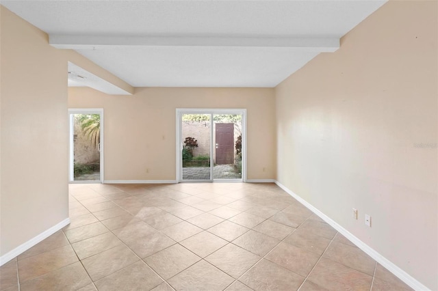 unfurnished room featuring beamed ceiling and light tile patterned flooring