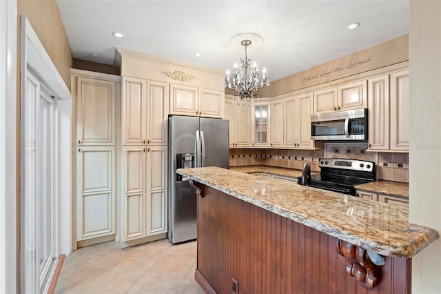 kitchen with cream cabinets, stainless steel appliances, decorative light fixtures, and a notable chandelier