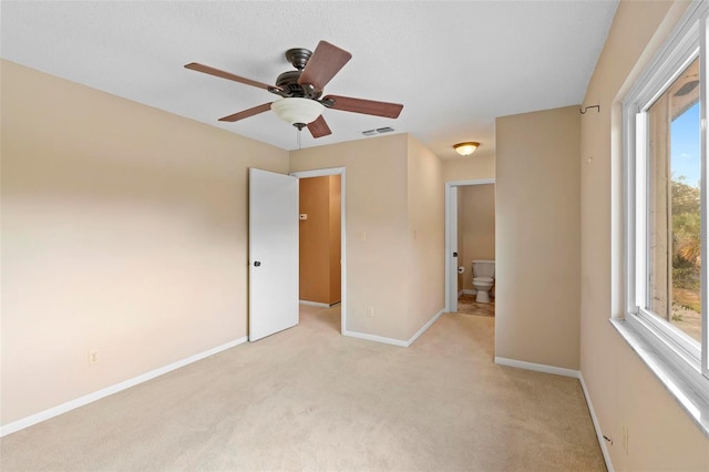 unfurnished bedroom with connected bathroom, ceiling fan, and light carpet