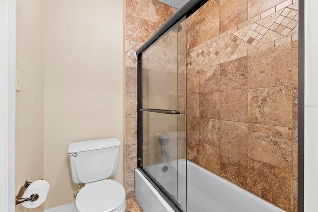 bathroom featuring toilet and bath / shower combo with glass door