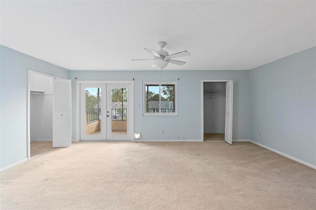 unfurnished bedroom with light carpet, french doors, ceiling fan, access to exterior, and multiple closets