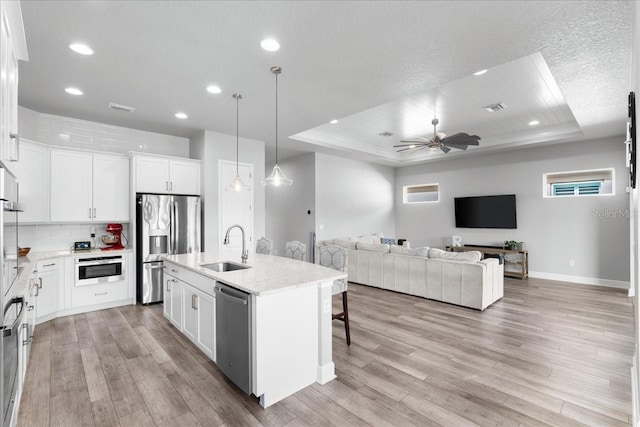 kitchen with white cabinets, sink, a raised ceiling, and an island with sink