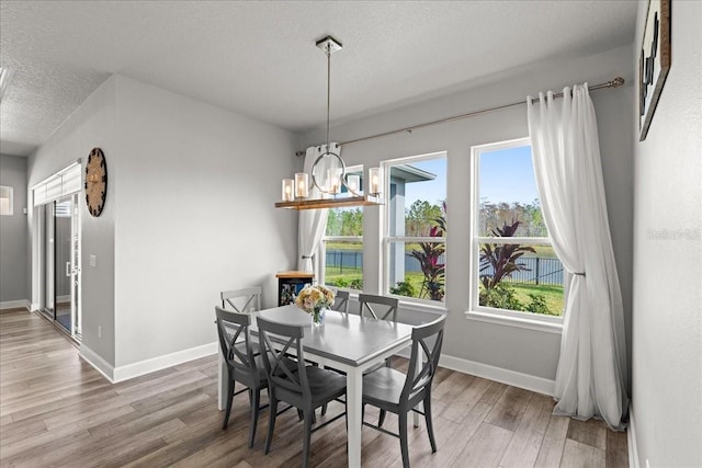 dining room featuring hardwood / wood-style floors, a water view, a textured ceiling, and a notable chandelier