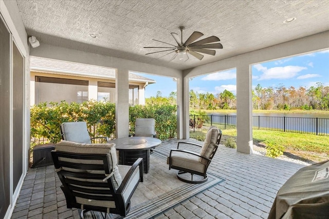 sunroom / solarium with a water view and ceiling fan