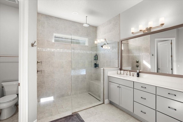 bathroom featuring tile patterned flooring, vanity, toilet, and a tile shower