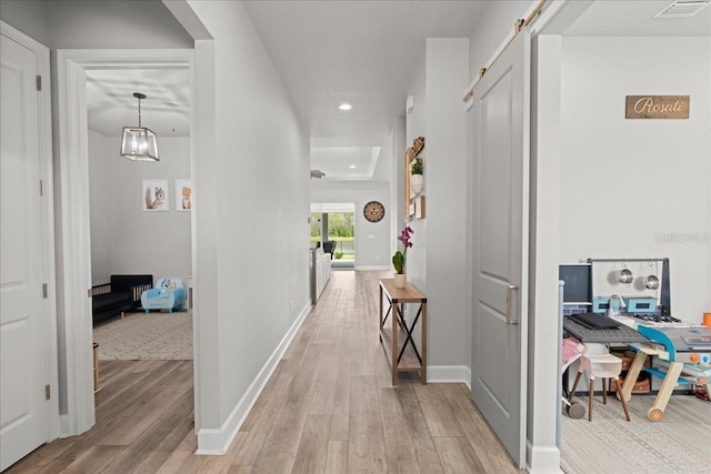 hallway featuring a barn door and light hardwood / wood-style flooring