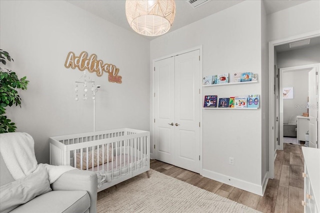 bedroom featuring wood-type flooring and a nursery area