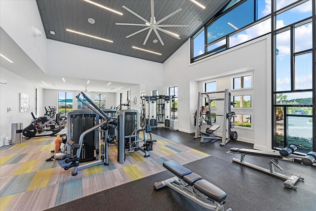 gym featuring ceiling fan, plenty of natural light, wood ceiling, and a high ceiling